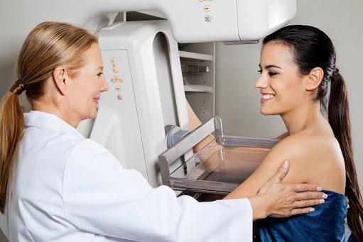 Mature female doctor assisting young patient during mammogram x-ray test